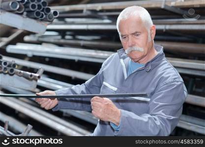 Senior worker looking at piece of metal
