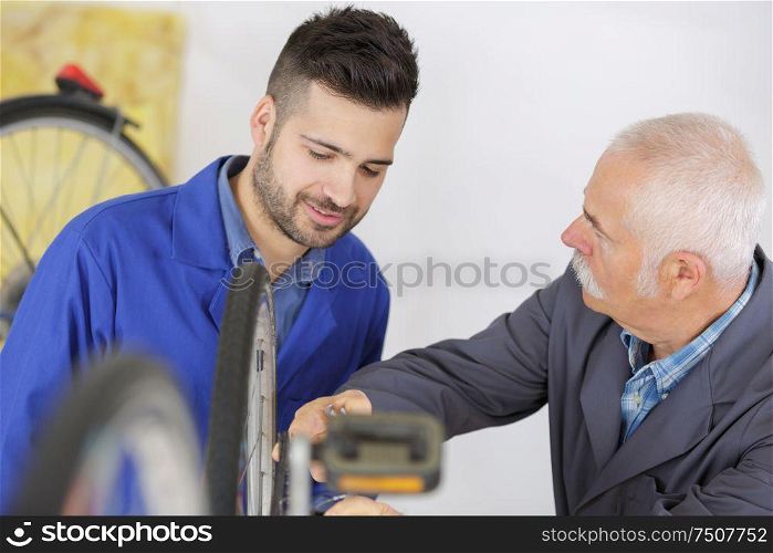 senior worker showing apprentice how to fix a bike