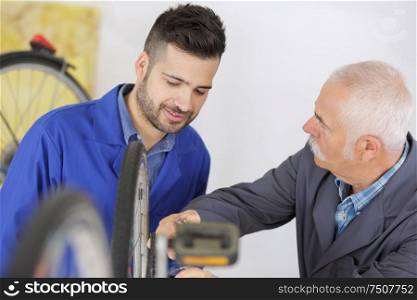 senior worker showing apprentice how to fix a bike