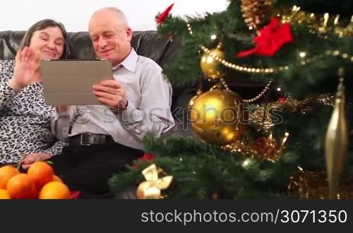 Seniors couple using tablet computer talking with video chat on Christmas.