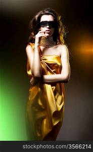 sensual adult woman in golden dress and black mask