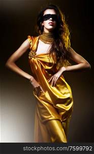 sensual adult woman in golden dress and mask