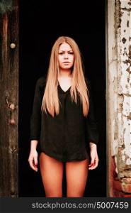 Sensual blonde girl in black shirt waiting near a wooden door
