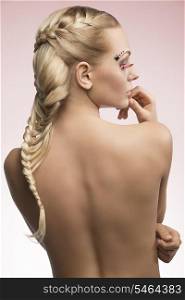 sensual blonde girl with creative long braid hair-style and feathered pink make-up turned on her back