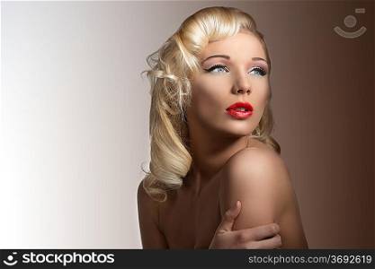 sensual blonde girl with vintage hairstyle and make-up, naked shoulders posing as a diva