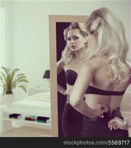 sensual blonde model with black bra undressing in front the mirror. Fashion glamour portrait