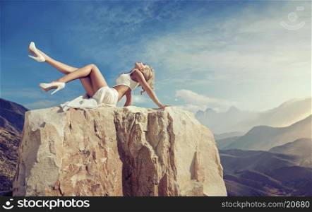 Sensual blonde relaxing on the sharp rock