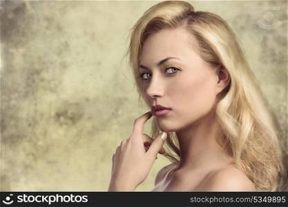 sensual blonde woman with long natural hair-style, colorful make-up and nude shoulders posing in close-up portrait and looking in camera with sensual expression