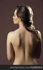 sensual brunette female showing her base back and creative elegant hair-style