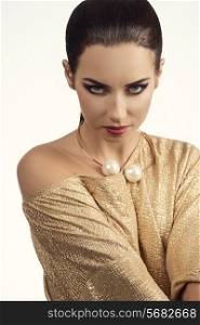 sensual brunette girl wearing elegant golden dress and necklace, showing her naked shoulder, looking in camera with charming eyes and stylish make-up