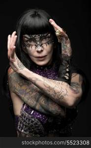 sensual carnival lady with brown smooth hair and tattoos wearing glitter bra, baroque mask and glitter bra