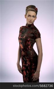 sensual caucasian woman posing in fashion shoot with oriental dress, creative hair-style and red rose in the hair. Sensual body, oriental style