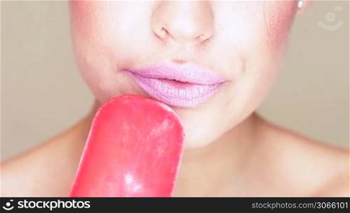 Sensual closeup of the mouth and tongue of an attractive woman licking an icecream lolly