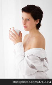 sensual coffee. sensual woman at a window holding coffee wearing a white button down shirt