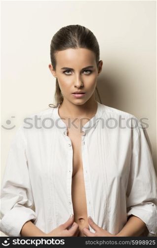 sensual cute girl with perfect skin posing in fashion beauty portrait with delicate make-up, open white shirt and looking in camera