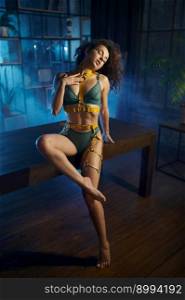 Sensual glamour shot of slim brunette woman posing for camera in lingerie and swordbelt over home kitchen interior in haze. Passion concept. Sensual glamour shot of slim brunette woman posing for camera in lingerie