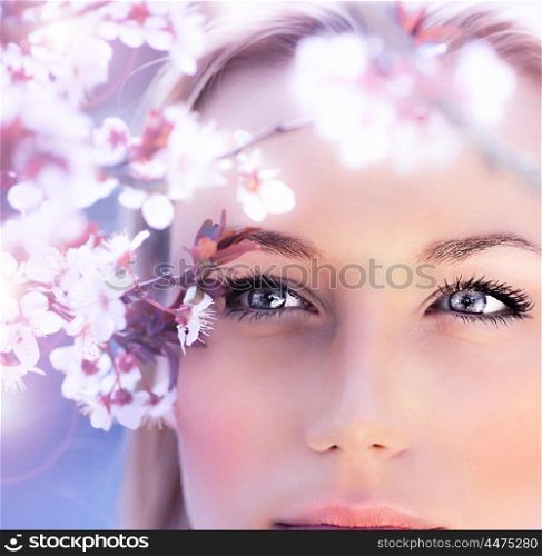 Sensual portrait of a spring woman, beautiful face, close up on blue eyes, female enjoying cherry blossom, dreamy girl with pink fresh flowers outdoor, seasonal nature, tree branch and natural beauty