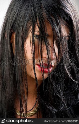 sensual portrait of black haired girl with red lips and hair on face