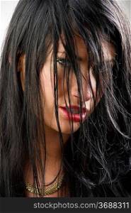 sensual portrait of black haired girl with red lips and hair on face
