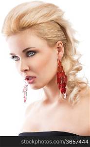 sensual portrait of very attractive blond woman with creative hair style and big fashion red earring with black top. she is turned of three quarters, looks in front of her with an expression of surpraise