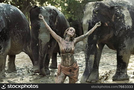 Sensual tamer playing with elephants in clay
