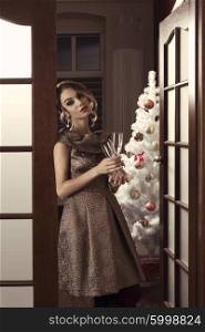 sensual woman with elegant rich style and hair-style posing in indoor portrait in christmas night with glasses in the hand for toast. Christmas tree and gift boxes on background