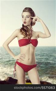sensual woman with long natural hair and sexy red bikini posing in summer shoot with funny pose