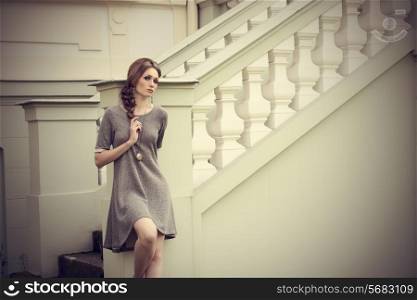 sensual young girl in fashion pose in outdoor location with elegant dress, stylish braid hair-style and cute jewellery