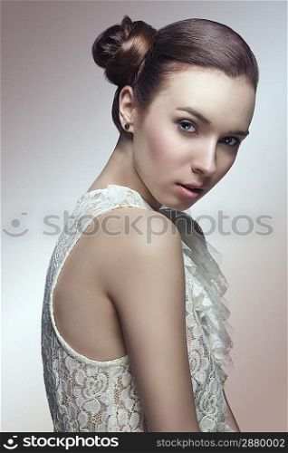 sensual young girl with brown hair tied in lateral chignon hair-style looking in camera and wearing sexy lace shirt