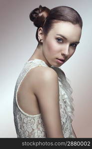 sensual young girl with brown hair tied in lateral chignon hair-style looking in camera and wearing sexy lace shirt