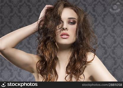 sensual young girl with brown hair, wavy wet hair-style and cute make-up, looking in camera with sexy expression on vintage background