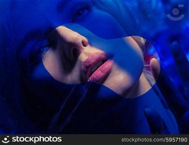 Sensual young lady behind blue wall