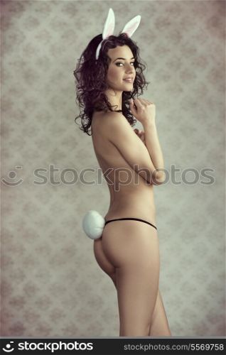 sensual young lady showing her perfect naked body and wearing only panties and pink rabbit ears and tail vintage color