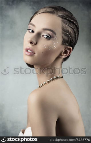 sensual young woman posing in romantic beauty portrait with creative plait hairdo, stylish necklace and brilliant make-up