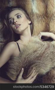sensual young woman posing in winter fashion shoot with creative make-up, natural hair-style, fluffy fur on her breast and on background. Glamour shoot