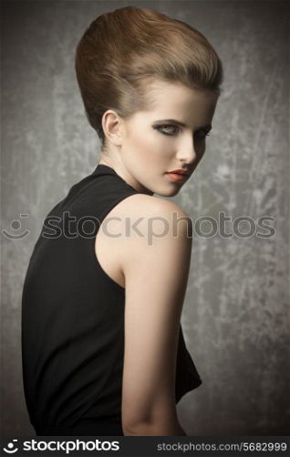 sensual young woman with charming eyes posing with stylish hair-style and make-up, wearing elegant black dress