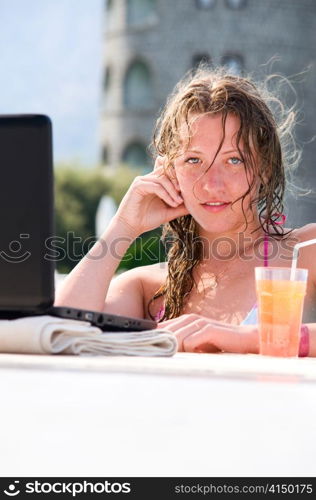 sensual young woman with laptop in swimming pool with cocktail