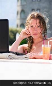sensual young woman with laptop in swimming pool with cocktail