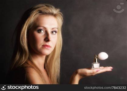 Sensuality concept. Portrait beautiful blonde woman with perfume bottle on black background