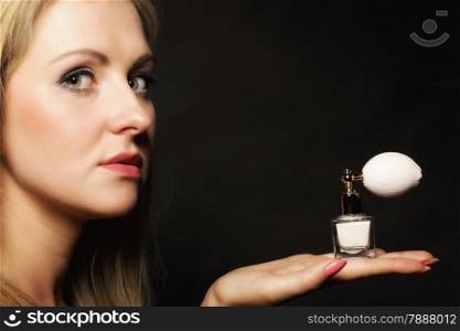 Sensuality concept. Portrait beautiful blonde woman with perfume bottle on black background