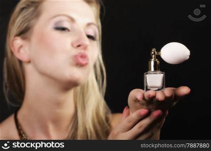 Sensuality concept. Portrait beautiful woman kiss on lips with perfume bottle on black background