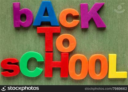 Sentence Back to school in colorful plastic letters over green background