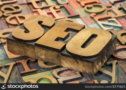 SEO (search engine optimization) acronym in wood type against background of letterpress printing blocks