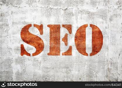 SEO (search engine optimization) sign painted in stencil font on an old, grunge stucco texture wall