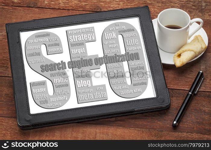 SEO - search engine optimization word cloud on a digital tablet with a cup of coffee