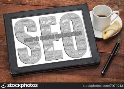 SEO - search engine optimization word cloud on a digital tablet with a cup of coffee