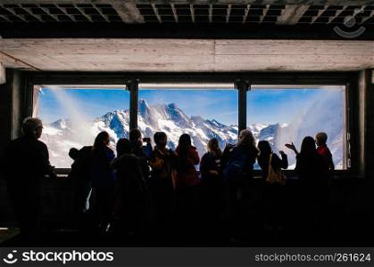 SEP 24, 2013 Jungfrau, Switzerland - Tourists enjoy Eiger and Monch peaks panoramic view through observation window of Eiger tunnel inside Swiss alps