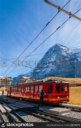 SEP 24,2013 Lauterbrunnen, Switzerland - Red Jungfrau railway train at Kleine Scheidegg station for Jungfraujoch with Swiss alps mountain Eiger and Monch peaks