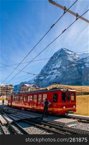 SEP 24,2013 Lauterbrunnen, Switzerland - Red Jungfrau railway train at Kleine Scheidegg station for Jungfraujoch with Swiss alps mountain Eiger and Monch peaks