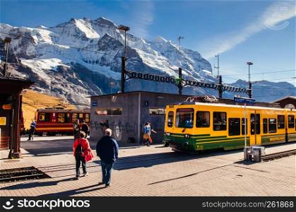 SEP 24,2013 Lauterbrunnen, Switzerland - Yellow Grindelwald train at Kleine Scheidegg station with Tschuggen peak on background, base station for Jungfraujoch